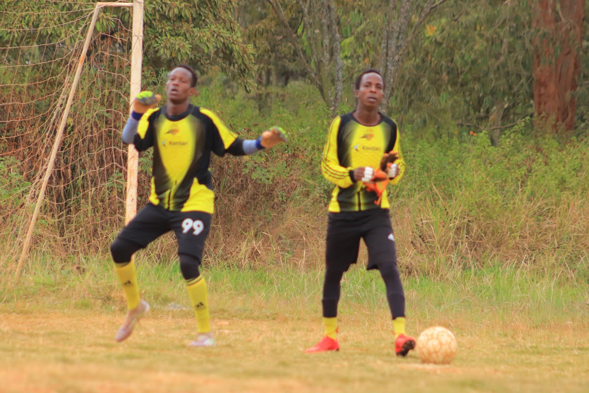Two goalkeepers in yellow and black kits preparing at the goal